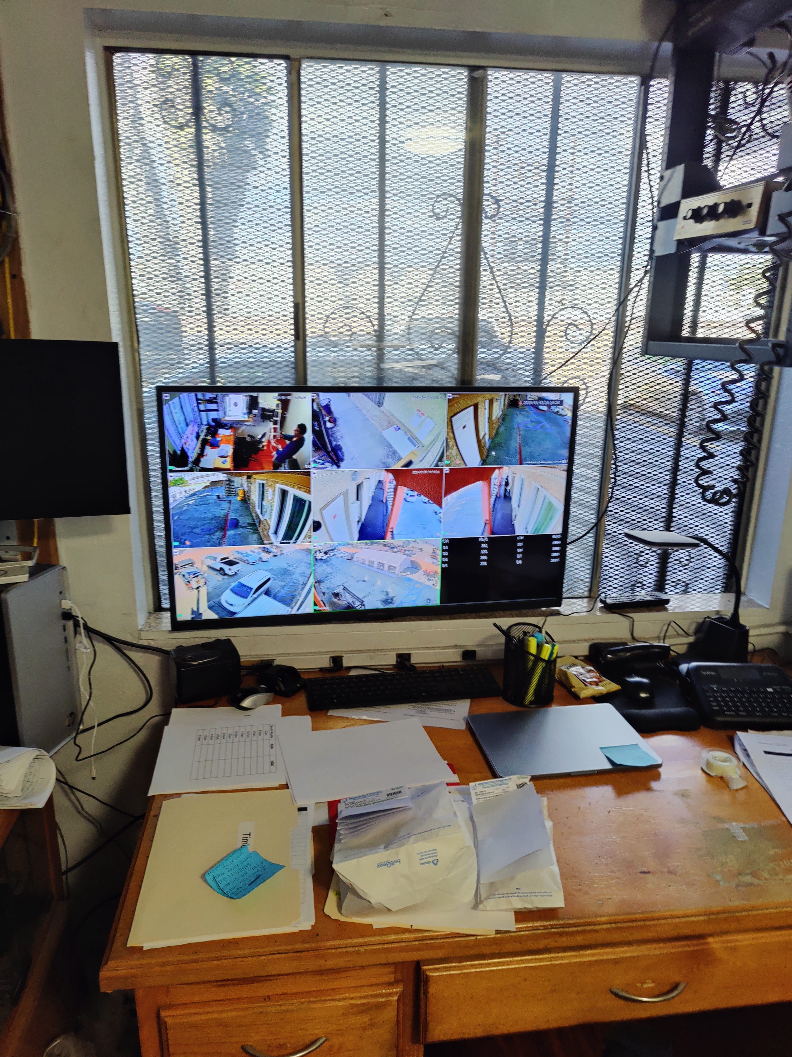 Office desk monitoring station with security camera grid view on screen