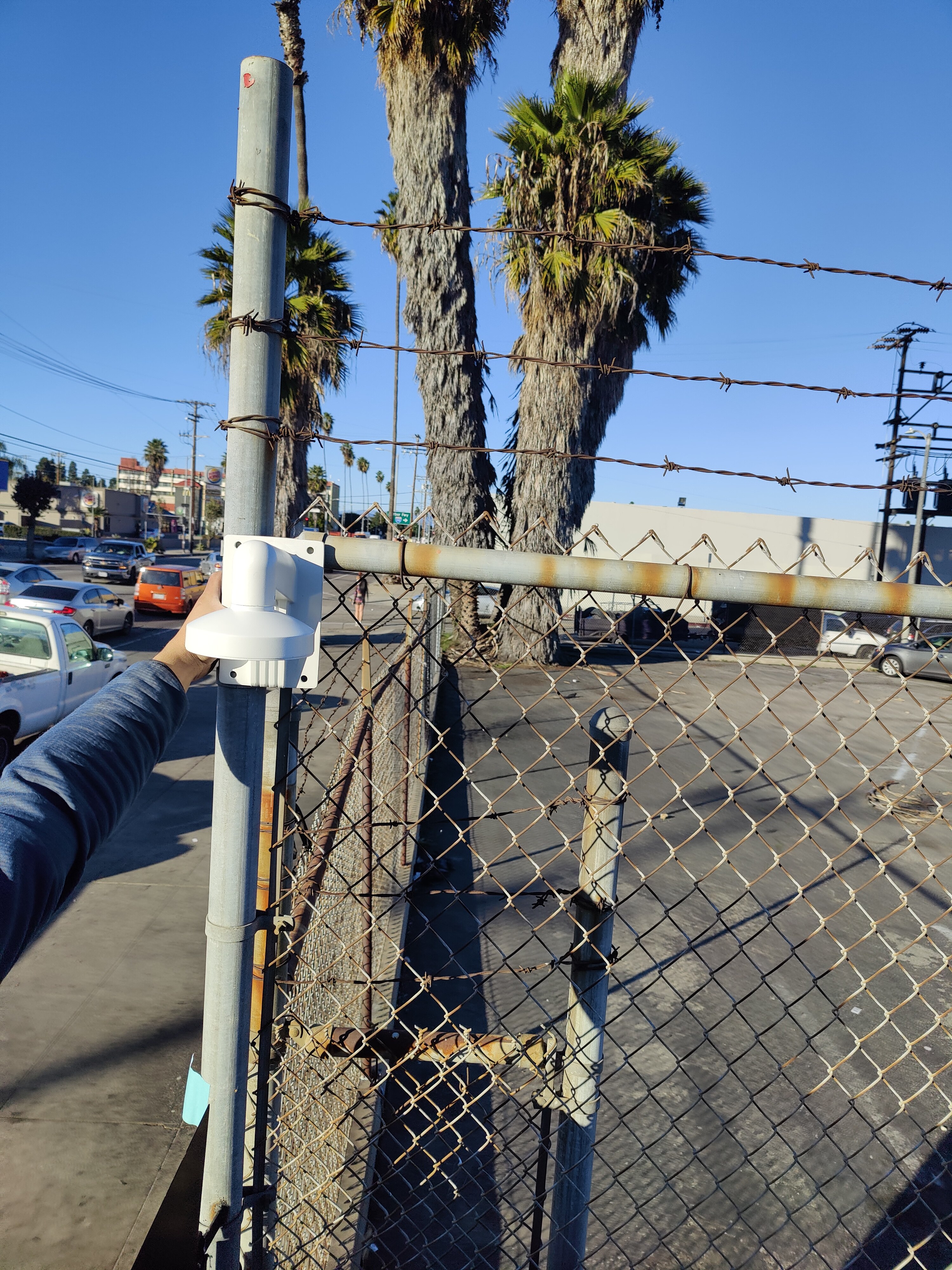 PTZ dome security camera being installed on commercial fence pole