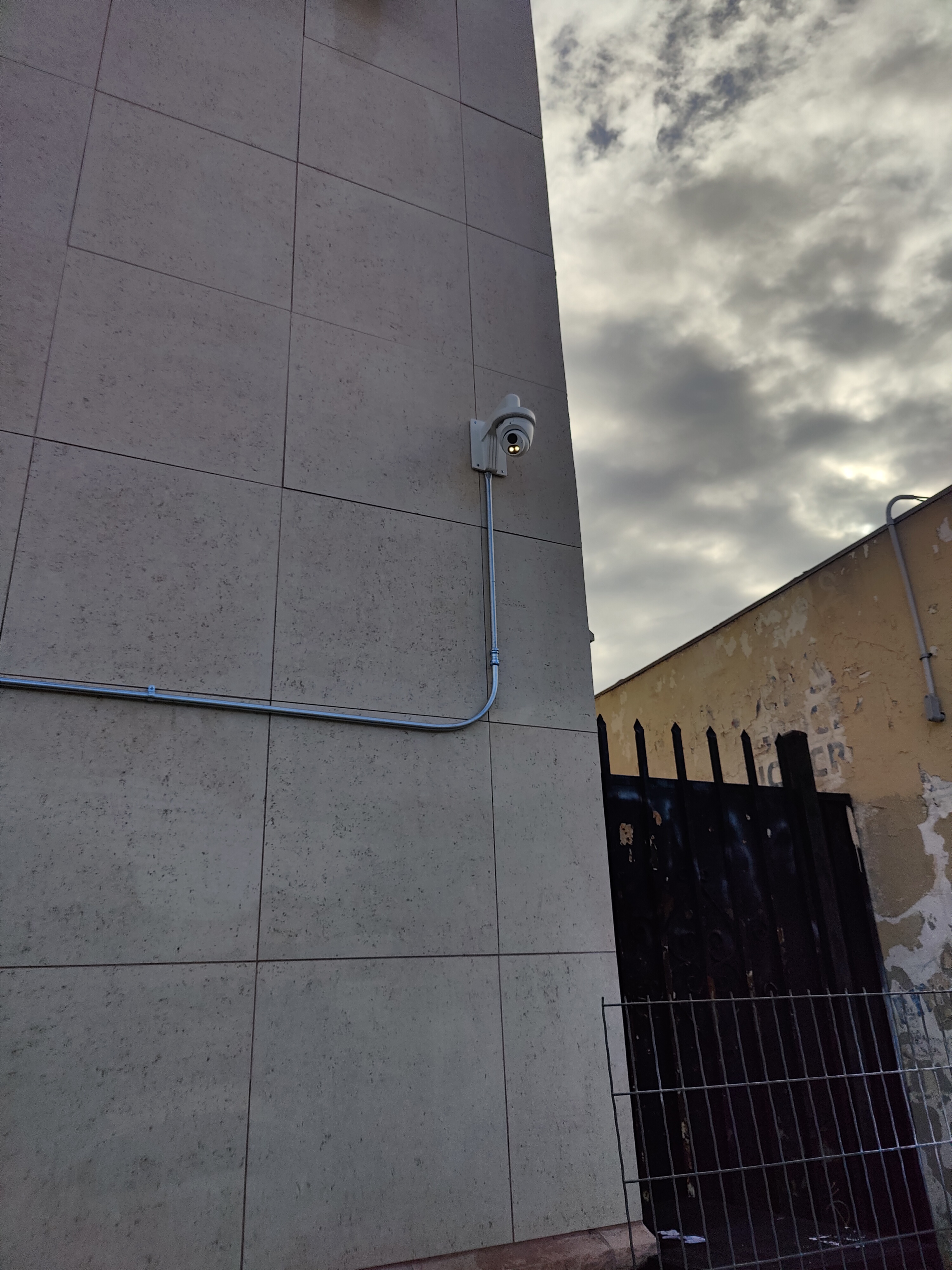 Security camera with conduit wall-mounted on commercial building exterior