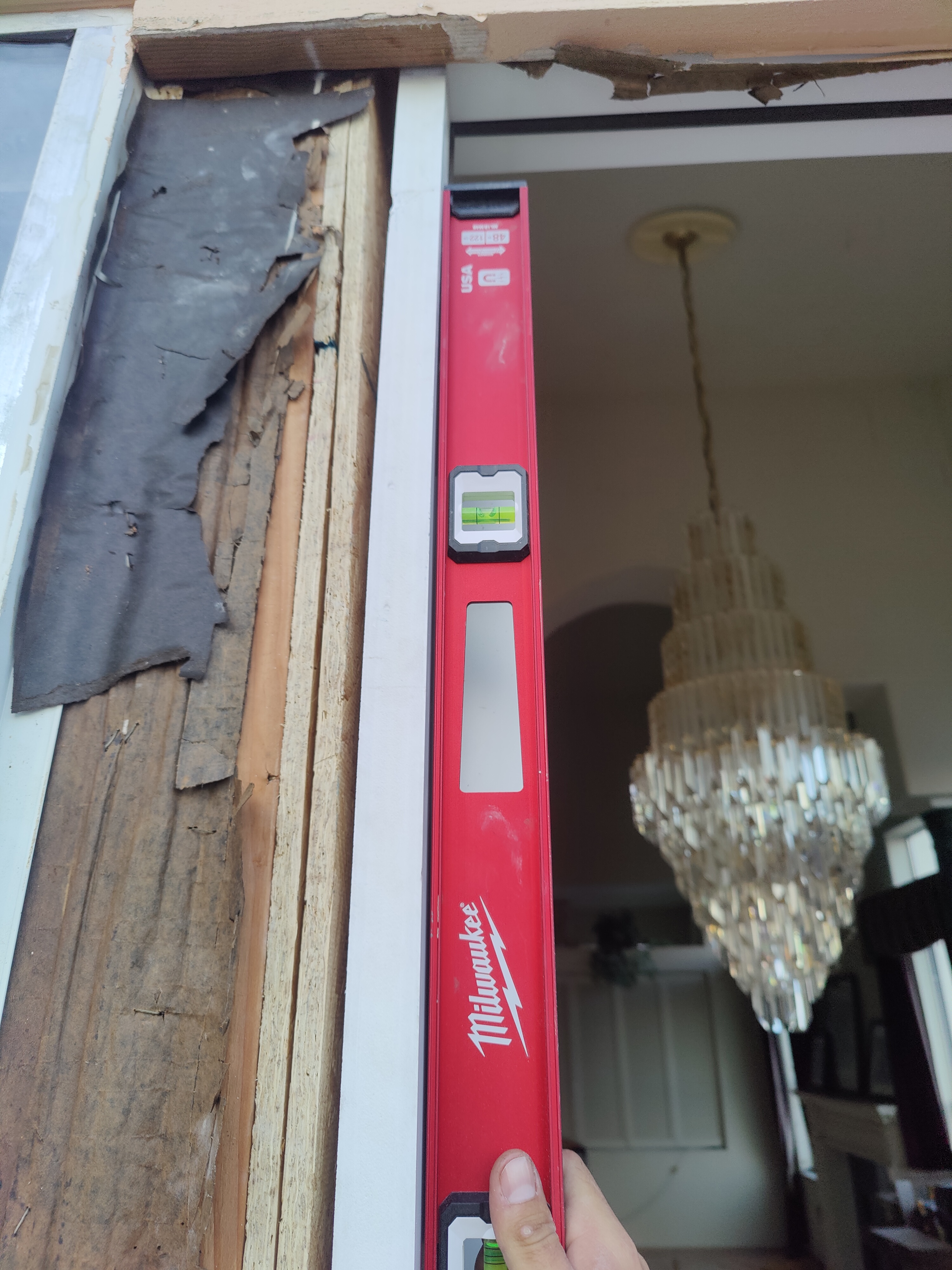 Checking plumb on new door frame with Milwaukee level during installation